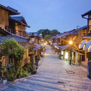 Old street of Kyoto in a Japanese town, lit by street lights under an early evening sky
