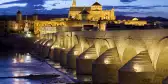 Roman Bridge on the Guadalquivir River and Mosque Cathedral, illuminated at dusk in Cordoba, Spain.
