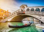 Gondola on Canal Grande with Rialto Bridge at sunset in Venice, Italy
