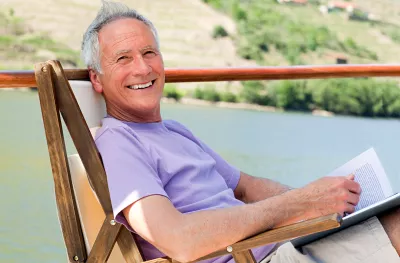 Smiling man relaxing in a chair while reading, on a boat deck