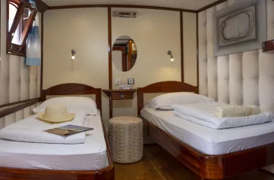 Interior shot of twin bedroom aboard the Ms Mendula cruise ship with glossy, wooden bedframes and fresh linen