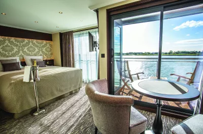 Deluxe suite bedroom with private balcony aboard the Thomas Hardy ship