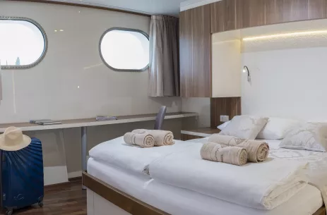 Twin bedroom with porthole window view aboard the Ms II Mare ship