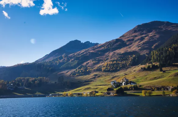 Lake of Davos and hills with sun and blue sky on a beautiful autumn day