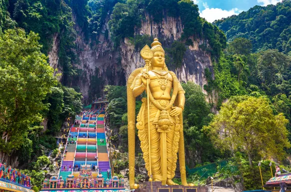 Entrance steps to Batu cave, Hinduism temple in Kuala Lumpur with colourful stairs and a large golden statue 