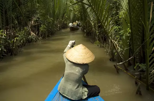 Vietnamese woman rowing a boat on the Mekong River in Vietnam