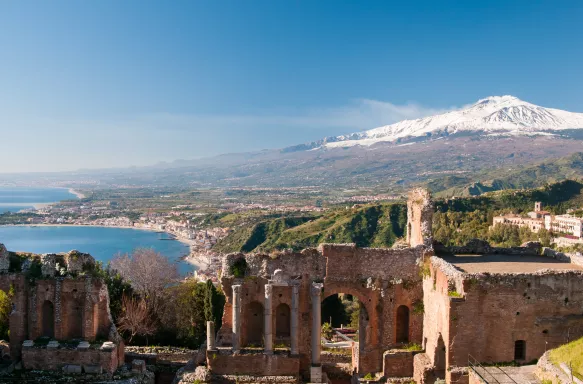 Taormina theatre columns with snowy Mount Etna in the distance in Taormina, Italy 