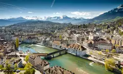 Lucerne ariel city view under warm-looking sunshine and a background of mountain peaks.