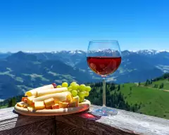 Fresh tirol cheese with wine and grapes over mountain landscape