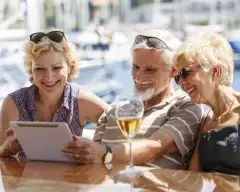 Senior friends smiling and using a digital tablet on a yacht.