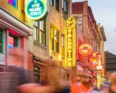Broadway pub district with colourful neon signs in downtown Nashville, with blurred passing figures