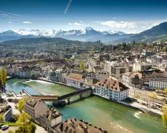 Lucerne ariel city view under warm-looking sunshine and a background of mountain peaks.