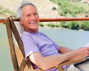 Smiling man relaxing in a chair while reading, on a boat deck