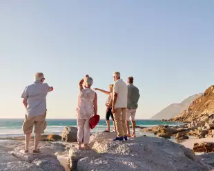 Rear view of senior friends standing on rocks looking out towards the sea