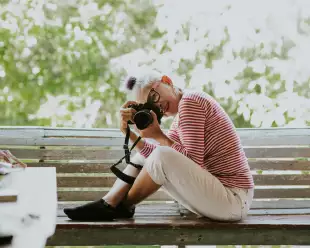 Senior Thai woman taking a professional photograph whilst sitting on a bench