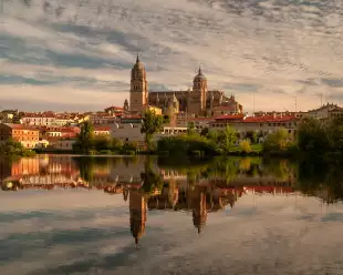 Salamanca Cathedral reflected on Tormes River during sunset in Salamanca, Spain