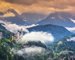 Neschwanstein Castle with vegetation and mist in the Bavarian Alps, Germany