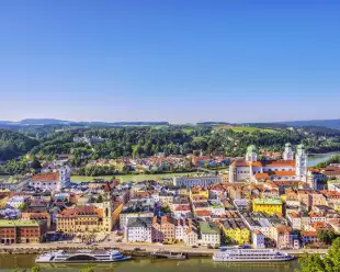 Elevated view of Passau, Germany, with sightseeing boats anchored in front of the town hall.