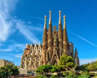 The La Sagrada Familia cathedral in Barcelona against a bright blue sky on a sunny day.
