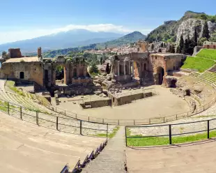 Ancient greek theatre ruins with views of Mount Etna in Taormina, Italy