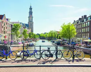 A view over a canal from a bridge with bicycles, boats and the Westerkerk in the back, Amsterdam.