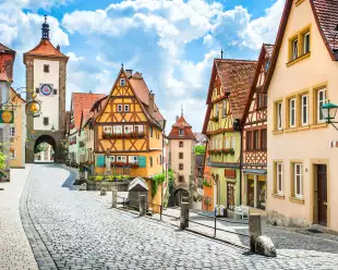 Historical half-timbered houses and cobbled streets of Rothenburg on a sunny day with blue sky and clouds in Franconia, Bavaria, Germany.