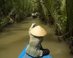 Vietnamese woman rowing a boat on the Mekong River in Vietnam