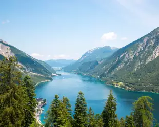 Alpine lake with fir trees and distant mountains  in Tyrol, Austria