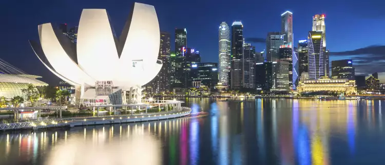 Singapore city skyline with high-rise buildings and lights reflecting on water at night