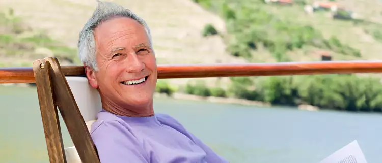 Smiling man relaxing in a chair while reading, on a boat deck