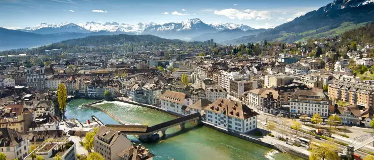 Lucerne ariel city view under warm-looking sunshine and a background of mountain peaks.