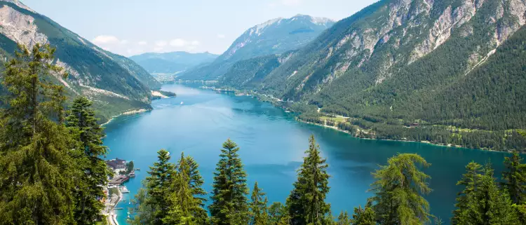 Alpine lake with fir trees and distant mountains  in Tyrol, Austria
